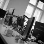 Rangee de postes de travail et d ecrans laisses allumes dans un bureau, vus en noir et blanc