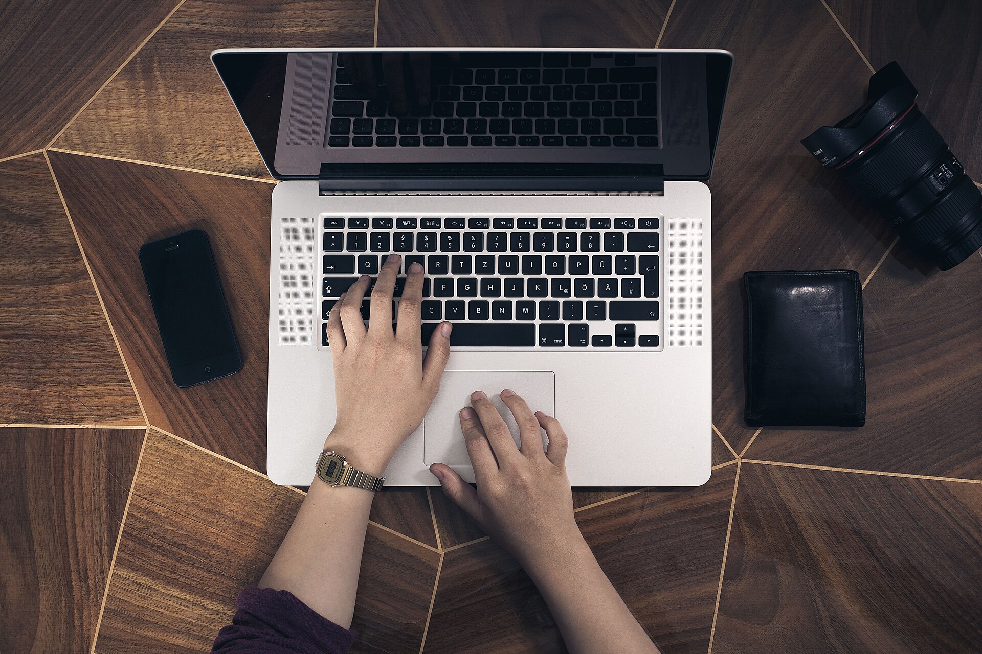 Mains sur le clavier d'un ordinateur portable vu de dessus sur un bureau en bois