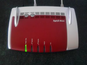 Routeur domestique posé sur un meuble, équipement qui fournit les serveurs DNS du réseau