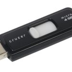 Cle USB SanDisk Cruzer posee a plat sur fond blanc, capuchon retire et connecteur USB visible