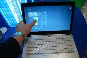 Doigt sur l'écran tactile d'un ordinateur portable affichant l'écran d'accueil de Windows