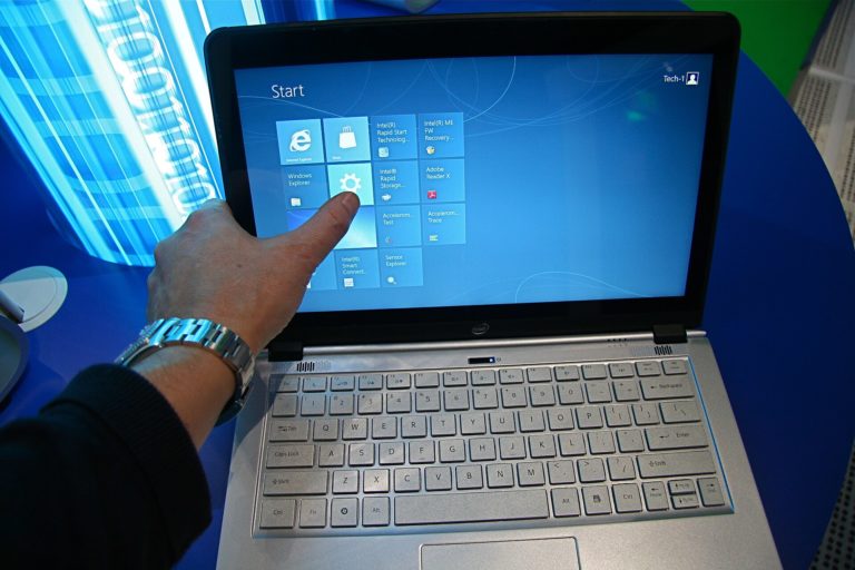 Doigt sur l'écran tactile d'un ordinateur portable affichant l'écran d'accueil de Windows