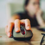 Main droite posée sur une souris d'ordinateur devant un clavier