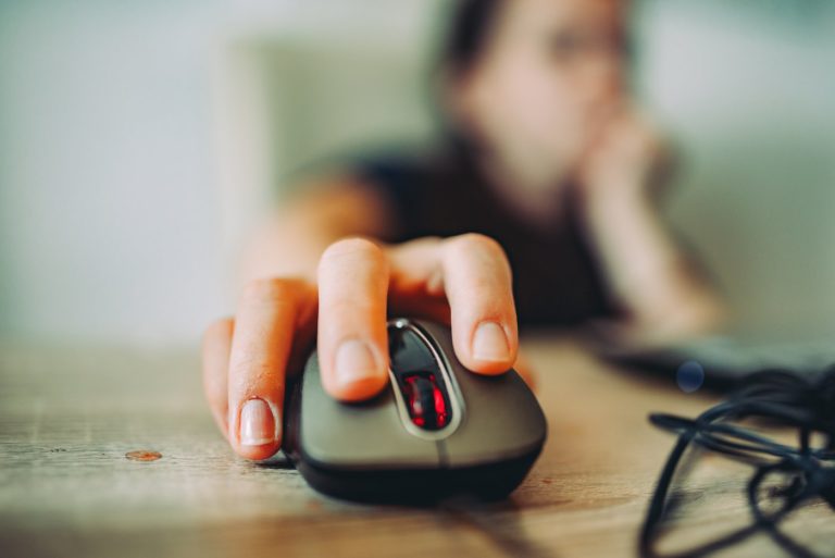 Main droite posée sur une souris d'ordinateur devant un clavier