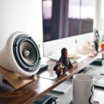 Bureau de travail avec un ordinateur portable, un clavier et une petite enceinte de bureau