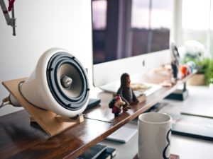 Bureau de travail avec un ordinateur portable, un clavier et une petite enceinte de bureau