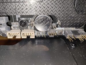 Pile bouton CR2032 installee sur une carte mere, a cote des connecteurs USB internes