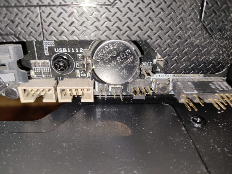 Pile bouton CR2032 installee sur une carte mere, a cote des connecteurs USB internes