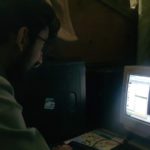 Personne assise devant un ordinateur de bureau ancien, ecran et clavier sur un plan de travail