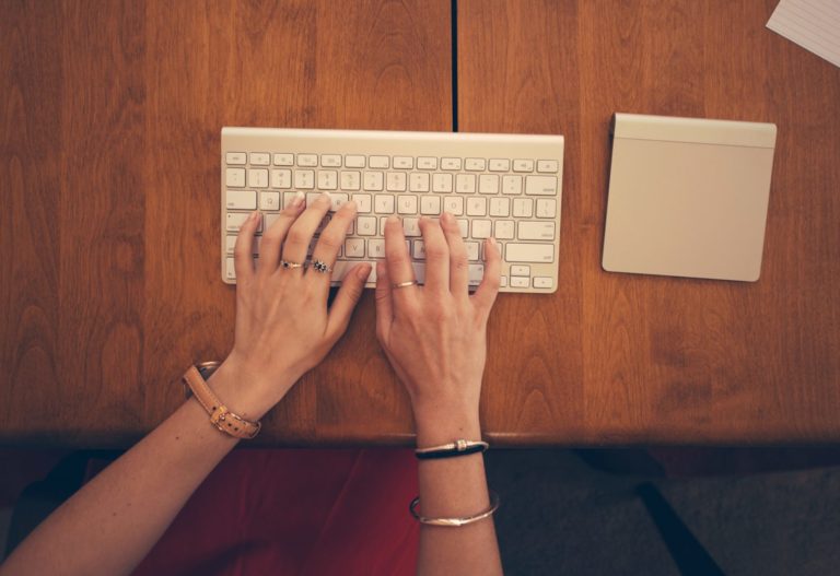 Mains tapant du texte sur un clavier d'ordinateur portable pose sur un bureau