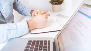 Porteur de projet qui prend des notes devant son ordinateur avant de lancer son projet web
